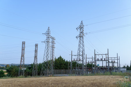 Electrical substation distributing electricity with high voltage towers and power lines under blue...