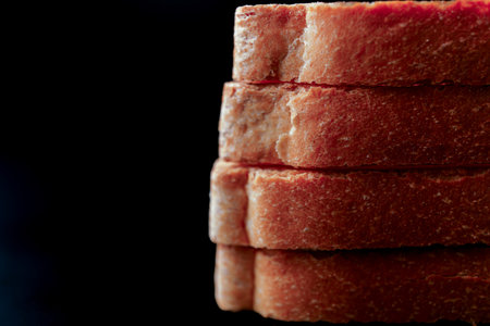 Close-up of toasted slices of bread loaf stacked on a dark background, creating a visually appealing imageの写真素材