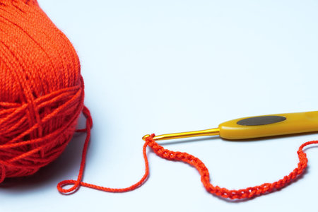 Red yarn and a crochet hook are used to create a chain stitch, a fundamental element in crochetの写真素材