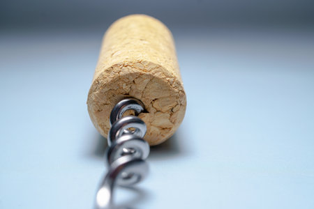 Close-up of metal corkscrew inserted into wine cork, representing the process of opening a bottle