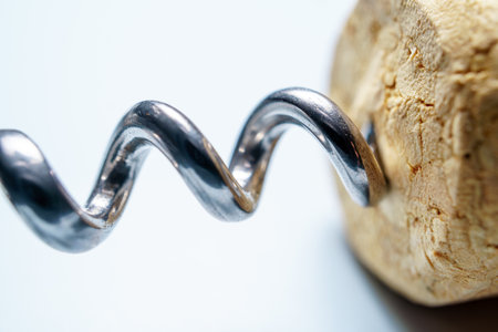 Metal corkscrew entering cork from wine bottle, isolated on white backgroundの写真素材