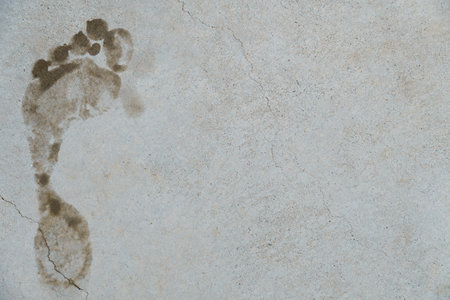 Footprint marking a gray concrete surface with cracks, symbolizing evidence, trace, or passage
