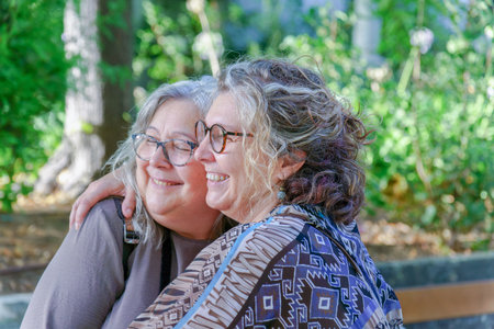 Two happy senior women hug in a park, enjoying a tender moment of affection and companionship, representing lgbtq love and visibilityの写真素材