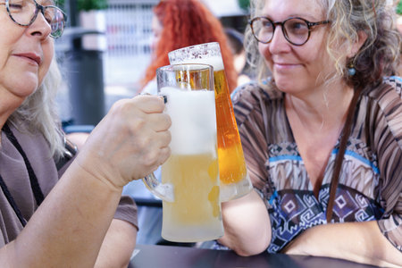 Women enjoying refreshing beer at a pub, celebrating friendshipの写真素材