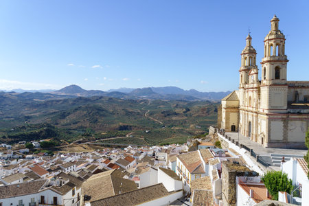 Olvera town perched on a hill, featuring its historic church and white houses, surrounded by olive fields in Olvera, Cadiz, Spainの写真素材