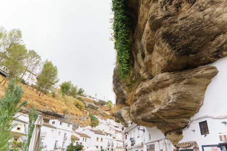 White houses constructed into massive rock overhangs, creating a unique and characteristic village in Andalusia, Spainの写真素材