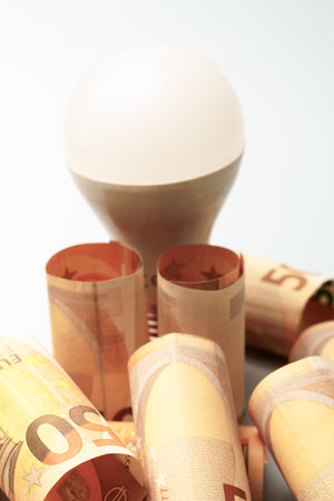 Led light bulb with rolled fifty euro banknotes, concept of energy cost, electricity bill, and saving moneyの写真素材