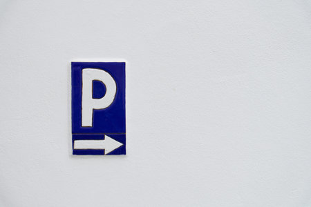 Blue and white parking sign indicating direction with a right arrow on a textured white wall backgroundの写真素材