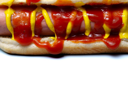 Hot dog bun cradle with a grilled frankfurter topped with ketchup and mustard, classic american fast food snack on a white background, close up, appetizing and simpleの写真素材