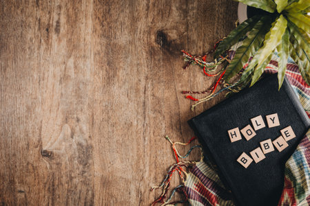 Holy Bible in block letters on a bible on a wooden table whit a blanket and a plant. Top view flat lay.の写真素材