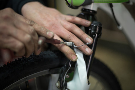 man repairing a bike with a screwdriverの写真素材