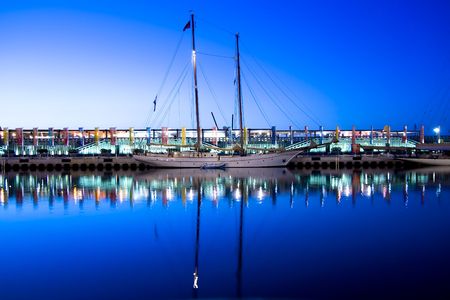 Sailboat reflected in the Valencia harbor water.
