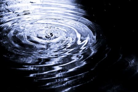 Drop rippled in dark blue water.の写真素材