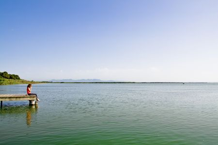 Young woman looking far over the lake.の写真素材