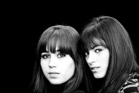 Two beautiful girls portrait in high key against black background.の写真素材