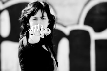 Young woman aiming at the camera. Focus in the gun barrel.の写真素材