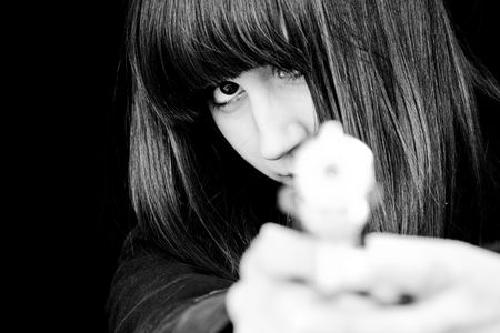 Mad woman aiming at you with a gun.の写真素材