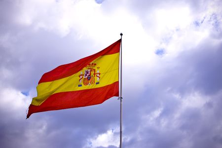 Spanish flag over stormy clouded sky.の写真素材