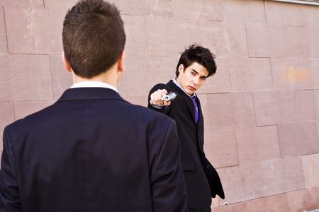 Well dressed man aiming to another with a gunの写真素材