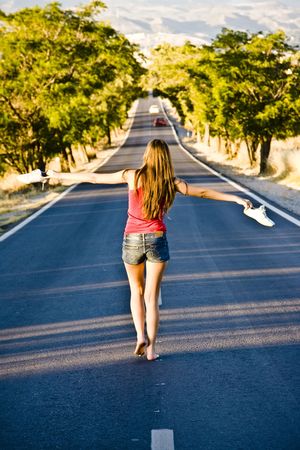 Young barefeet woman balancing in the middle of the roadの写真素材