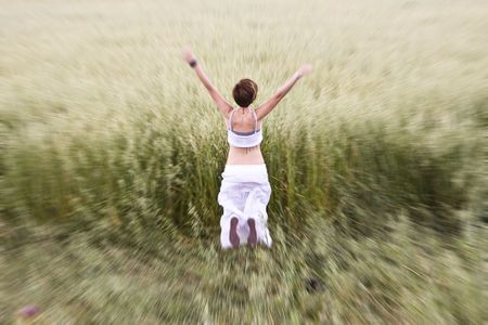 Young blond woman jumping in meadow.の写真素材