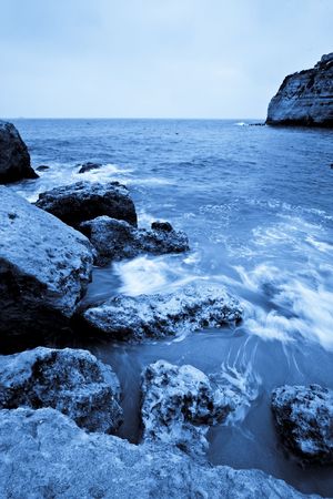 Long exposed waves in a beach full of rocks.の写真素材