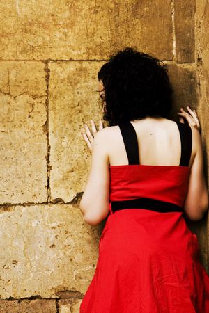 Sad young woman with her face against a wallの写真素材