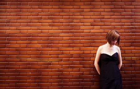 Sad woman portrait posing over red brickwallの写真素材