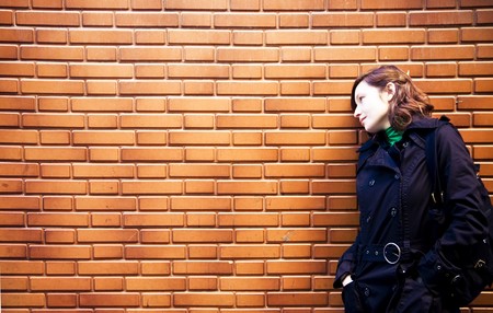 Young urban woman over brickwall, free copy spaceの写真素材