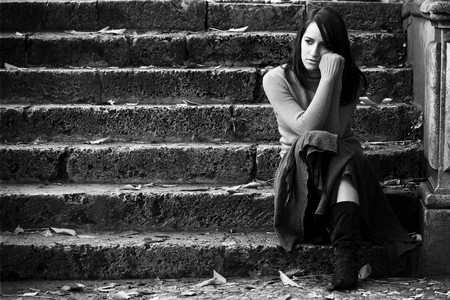 Young thoughtful woman sitting in stone stairs.の写真素材