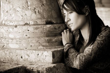 Young worried woman against old stone columnの写真素材