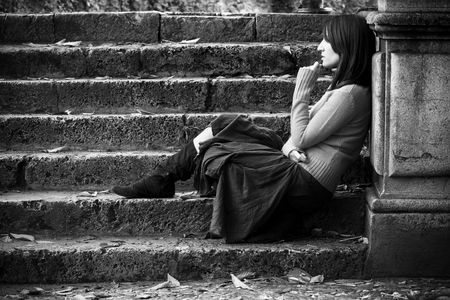 Young thoughtful woman sitting in stone stairs.の写真素材