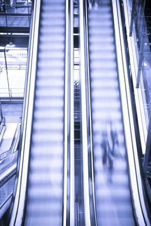 Blurred person on moving escalators, blue toned.の写真素材