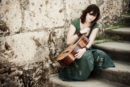 Young female guitarist on antique backgroundの写真素材