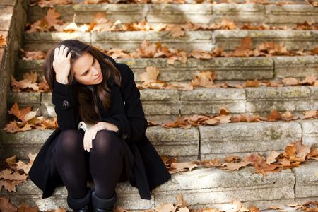 Young beautiful thoughtful girl in autumn backgroundの写真素材