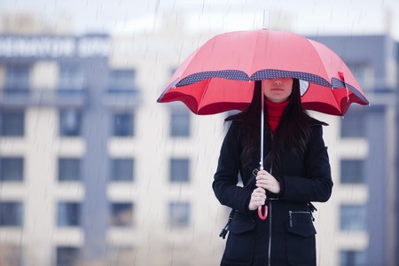 Young girl hidden under umbrella while it´s rainingの写真素材