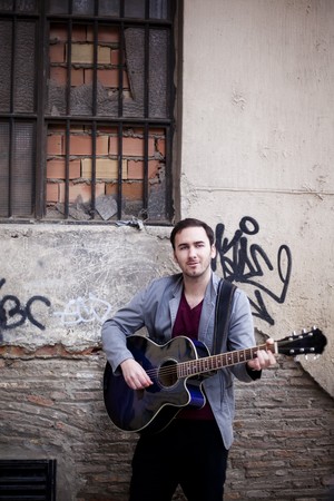 Young atractive street artist playing guitar.