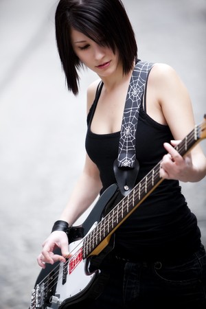 Dark haired beautiful girl playing her electric bass.の写真素材
