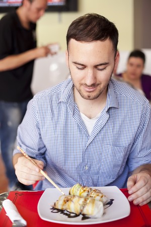 Young man in thai restaurant, unrecognizable people on the backgroundの写真素材