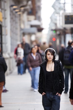 Young girl with headphones standing on sidewalkの写真素材