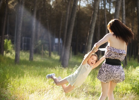 Mom playing with her daughter in sunny outdoorsの写真素材