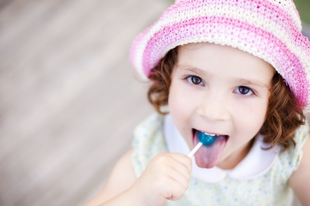 Little kid enjoying a lollypop while staring at camera from belowの写真素材