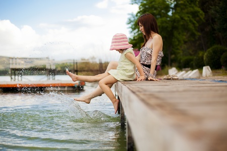 Young mother and her daughter splashing in the lakeの写真素材