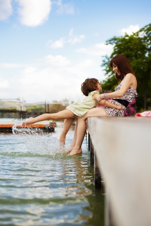 Young mother and her daughter splashing in the lakeの写真素材