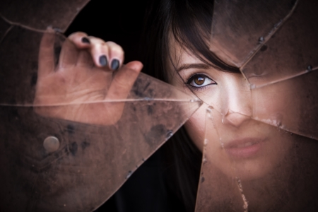 Woman looking through dirty broken glassの写真素材