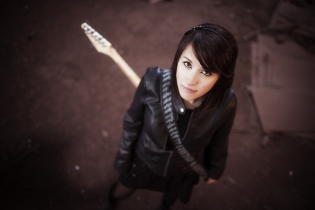 Young beautiful female performer posing with her electric guitar.の写真素材