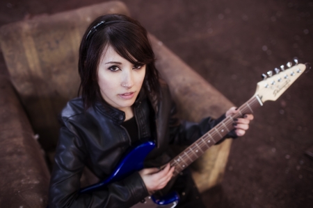 Young beautiful female performer posing with her electric guitar.の写真素材