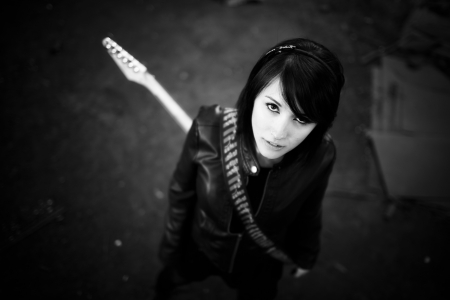 Young beautiful female performer posing with her electric guitar.の写真素材