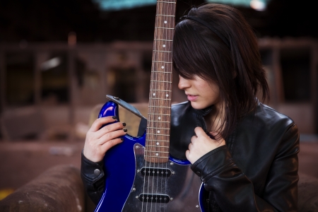 Young beautiful female performer posing with her electric guitar.の写真素材