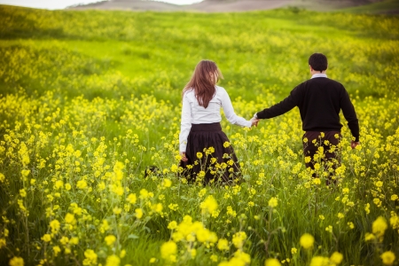 Young coupletaking a walk on beautiful flower field.の写真素材